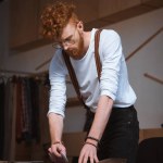 Focado jovem designer de moda masculina trabalhando com tecido na oficina