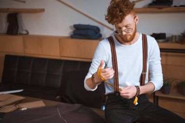 genç erkek moda tasarımcı atölyesinde ölçüm bandı tutan gözlük