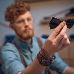 Close-up view of young male fashion designer holding black bow tie