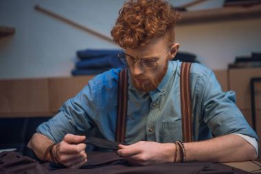 genç erkek moda tasarımcısı gözlük masada kumaş ile çalışma