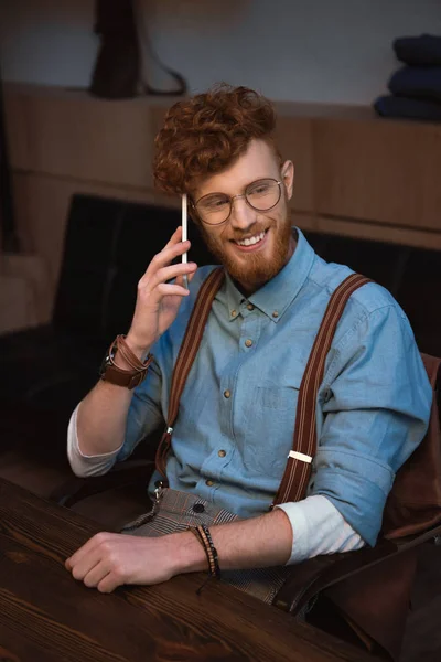 スマート フォンで話していると笑顔の眼鏡の若い赤毛のハンサムな男 — ストック写真