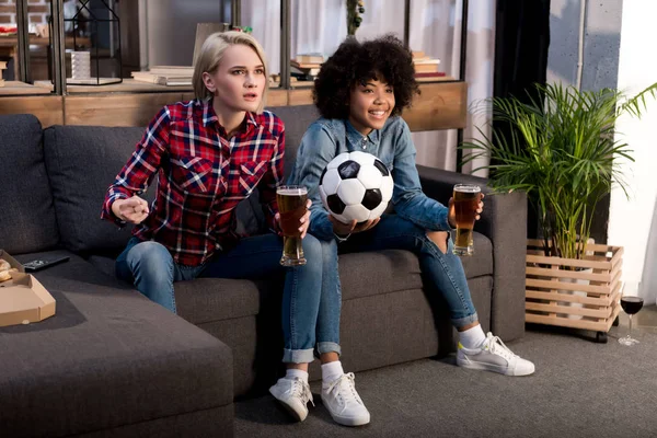 ビールとテレビでサッカーを見ている多文化の女の子 — ストック写真