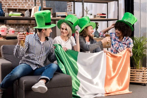 Amigos Multiétnicos Celebrando Día San Patricio Casa Sosteniendo Bandera Irlandesa —  Fotos de Stock