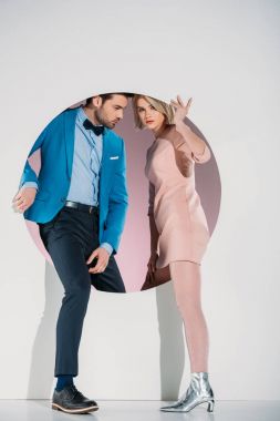 fashionable couple in love stepping through hole on grey  