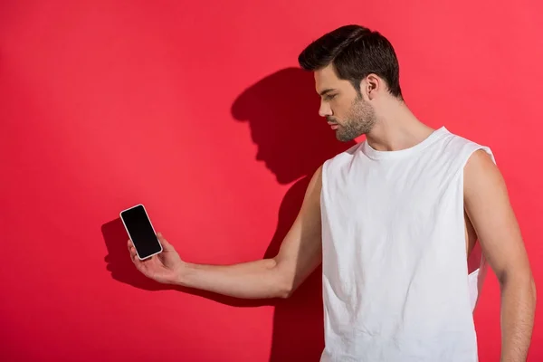 年轻英俊的男子手持智能手机与空白屏幕粉红色 — 图库照片
