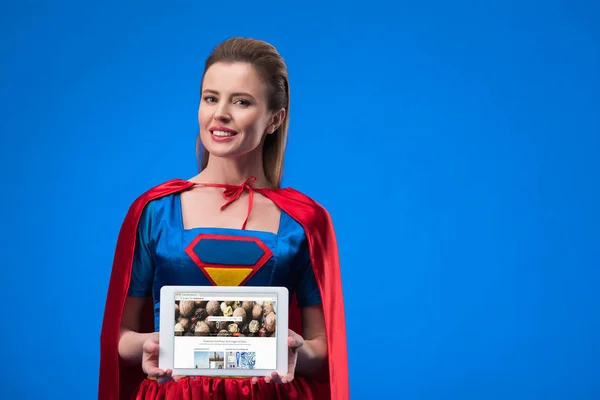 Portrait Smiling Woman Superhero Costume Showing Tablet Isolated Blue — Stock Photo, Image