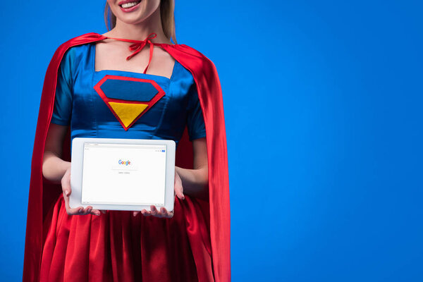 partial view of woman in superhero costume showing tablet isolated on blue