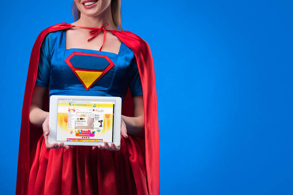 partial view of woman in superhero costume showing tablet isolated on blue