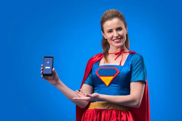 Portret Van Lachende Vrouw Superheld Kostuum Toont Smartphone Met Facebook — Stockfoto