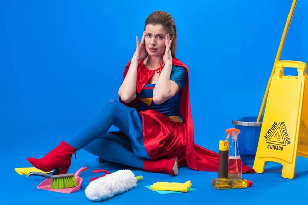 クリーニング用品に分離された青の周りでスーパー ヒーローの衣装で疲れている女性 — ストック写真