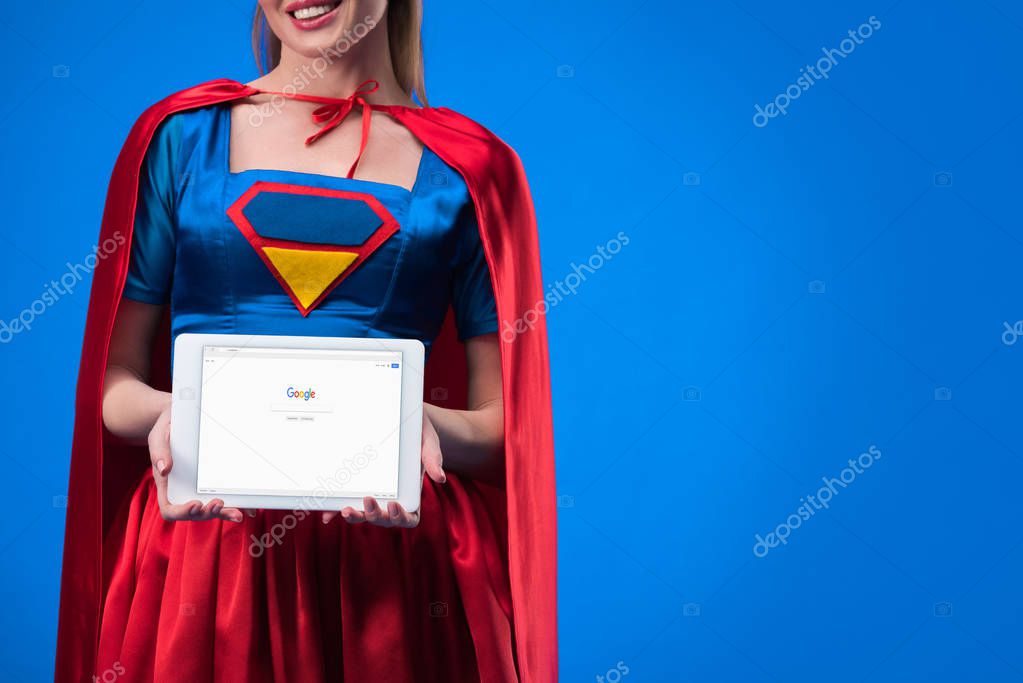 Partial view of woman in superhero costume showing tablet isolated on blue