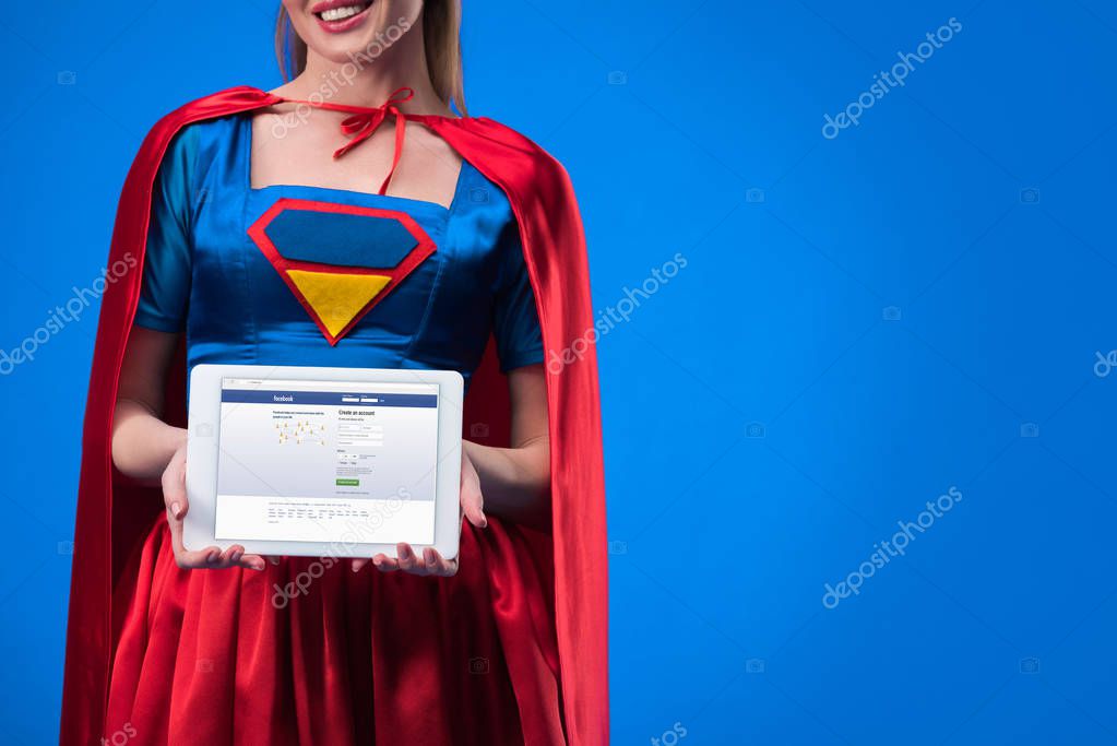 Partial view of woman in superhero costume showing tablet isolated on blue