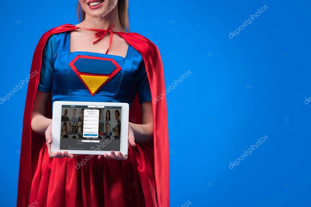 Partial view of woman in superhero costume showing tablet isolated on blue