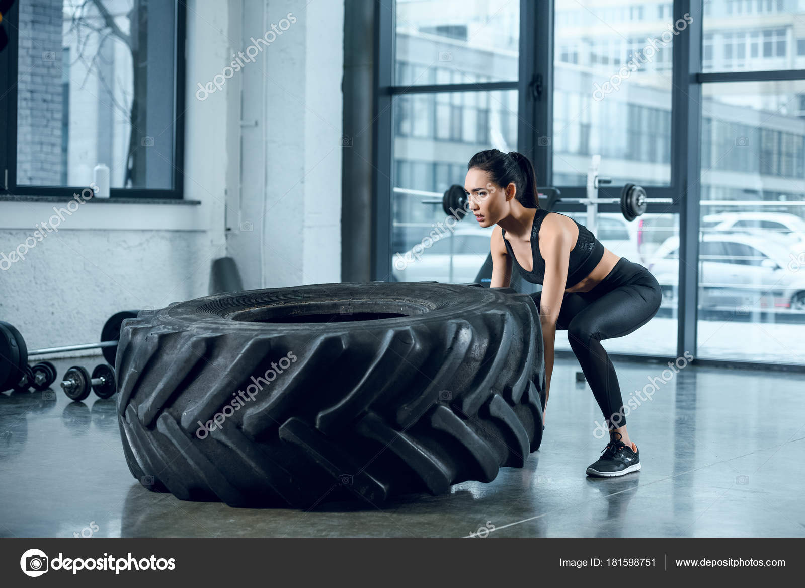Young Athletic Woman Flipping Workout Wheel Gym Stock Photo by
