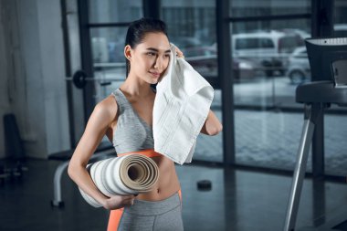 sonra egzersiz spor salonunda ter havlu ile silerek haddelenmiş yoga mat olan sportif kadın