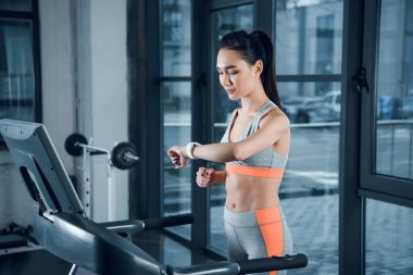 genç atletik sporcumuz spor salonunda treadmill çalıştırırken Fitness izci kontrol
