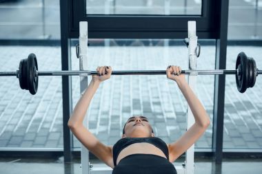 genç kadın spor salonunda bankta yalan sırasında halter kaldırma yerleştirmek