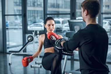 genç kadın savaşçı spor salonunda antrenör ile düşük tekme gerçekleştirme