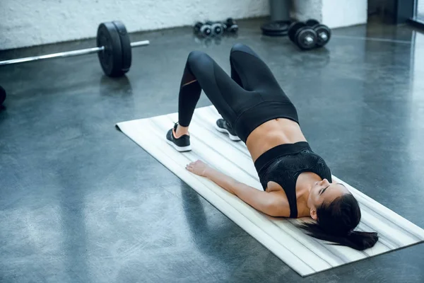 年轻运动的妇女做桥梁锻炼在健身房 — 图库照片