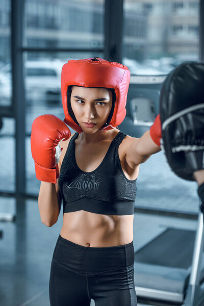 equiped sporty female boxer training at gym
