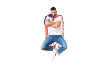 handsome young man with american flag jumping with crossed arms and looking at camera isolated on white clipart