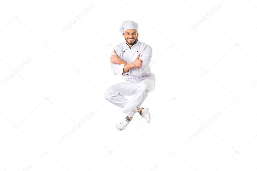 happy young male chef showing thumbs up and smiling at camera isolated on white 