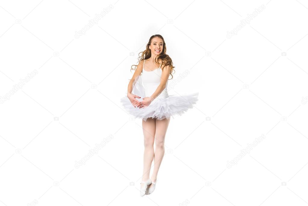 happy young ballerina dancing and smiling at camera isolated on white