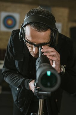 man looking through binoculars in shooting range