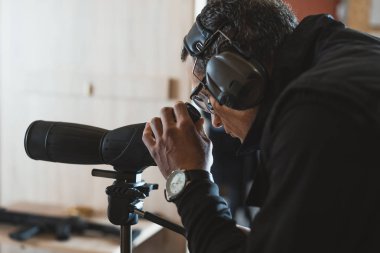 man looking through binoculars in shooting range clipart