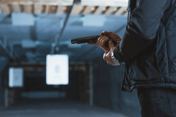 cropped image of man putting magazine into gun