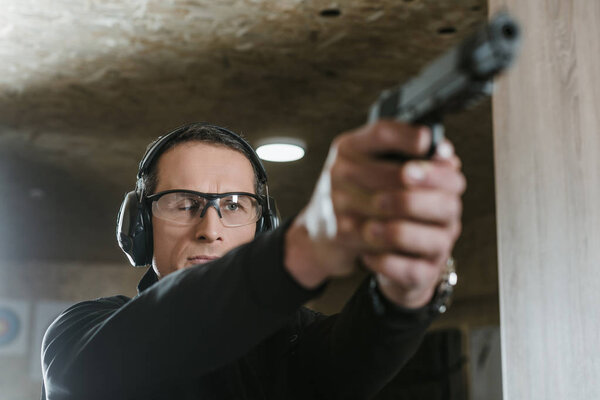 man aiming gun at target in shooting range