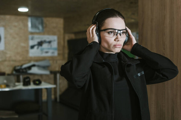 attractive girl wearing hearing protectors in shooting range
