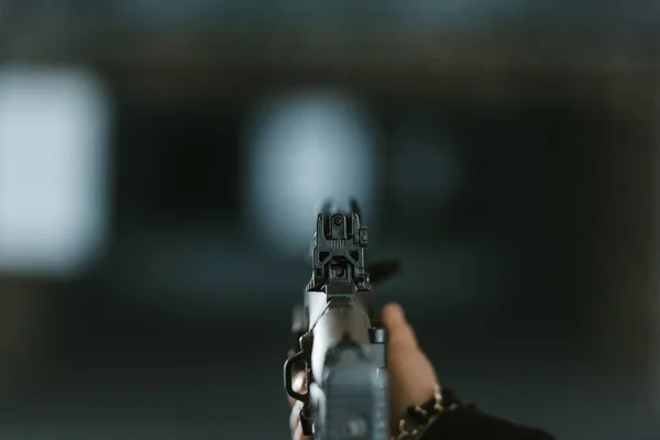 cropped image of man aiming rifle at target in shooting range