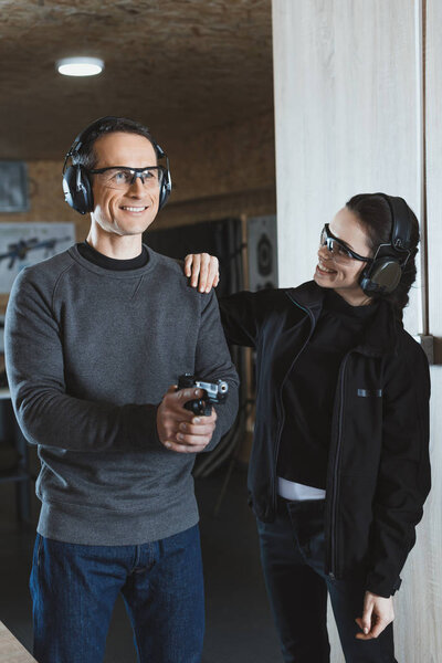 инструктор по стрельбе, помогающий клиенту в стрельбище
