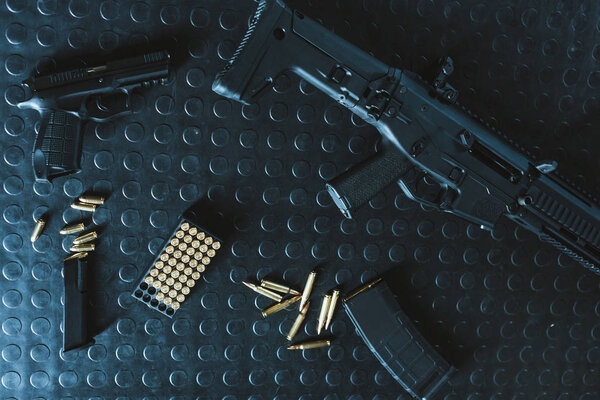 вид сверху на пистолет и винтовку с пулями на столе
