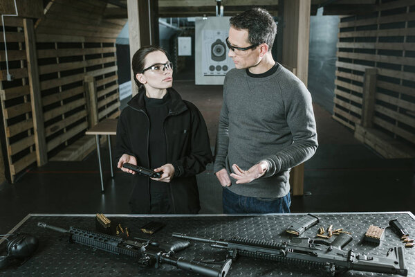 instructor describing gun to female client in shooting range