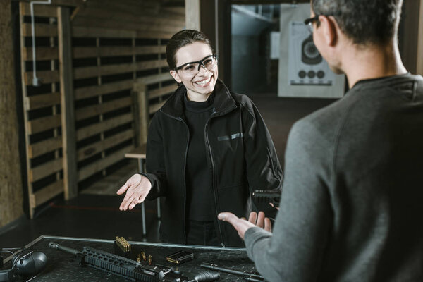 smiling customer talking with shooting instructor in shooting range