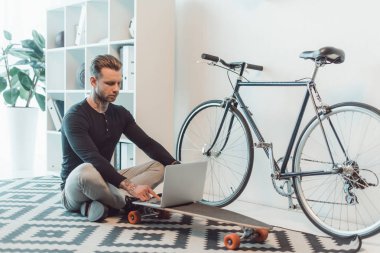 katta oturan ve kaykay üzerinde dizüstü kullanarak genç işadamı