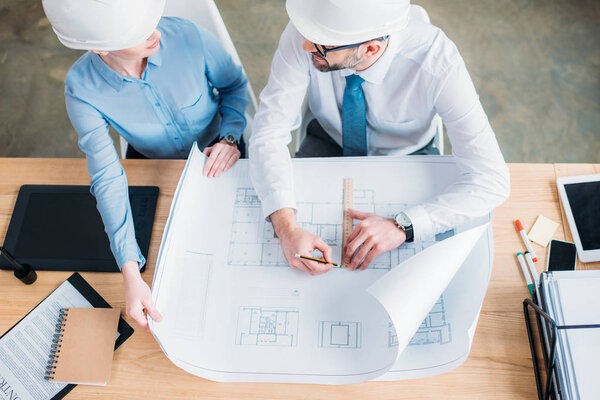 high angle view of experienced architects working with building plan at office