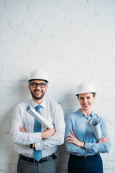 Smiling Architects Hard Hats Standing Front White Brick Wall Blueprints — Stock Photo, Image