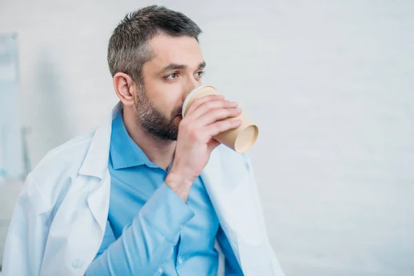 Exhausted Doctor Drinking Coffee Paper Cup Looking Away — Stock Photo, Image