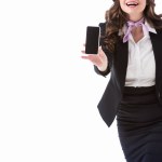 Обрезанное изображение смеющейся стюардессы, показывающей смартфон с пустым экраном, изолированным на белом Обрезанное изображение смеющейся стюардессы, показывающей смартфон с пустым экраном, изолированным на белом