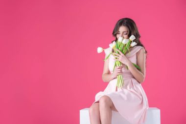 attractive girl sniffing bouquet of tulips isolated on pink clipart