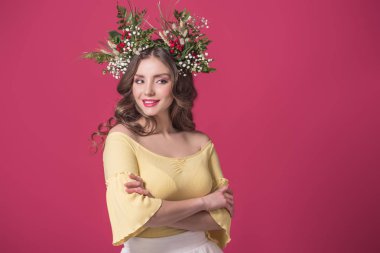 beautiful girl with flowers wreath on head standing with crossed arms isolated on burgundy clipart