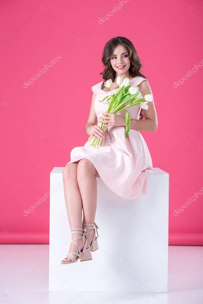 attractive girl with bouquet of tulips looking away on pink