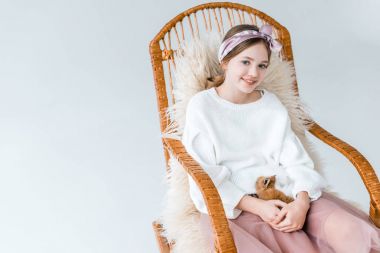 tavşan tutarak ve üzerinde beyaz izole sallanan sandalyede oturan ise kameraya gülümseyen güzel kız