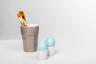 mavi boyalı Paskalya yumurtaları ve Boya fırçaları Kupası'nda yakından görmek Grey