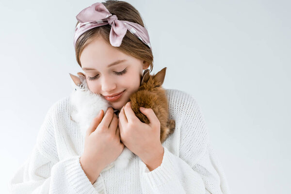 happy little girl holding cute furry rabbits isolated on white