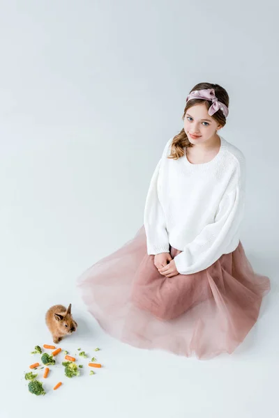 Adorável Menina Sorrindo Para Câmera Enquanto Alimentando Coelho Isolado Branco — Fotografia de Stock Grátis