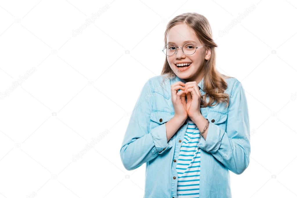 happy girl in eyeglasses showing hand heart symbol and smiling at camera isolated on white